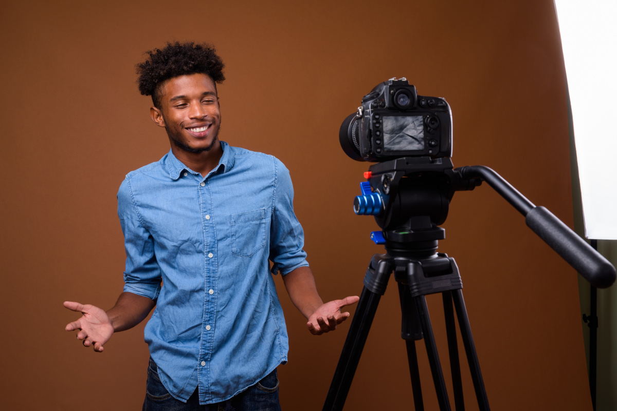 Studio shot of young handsome African man wearing smart casual clothing against brown background